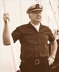 LRH in a short sleeve shirt and captain hat standing on a boat.